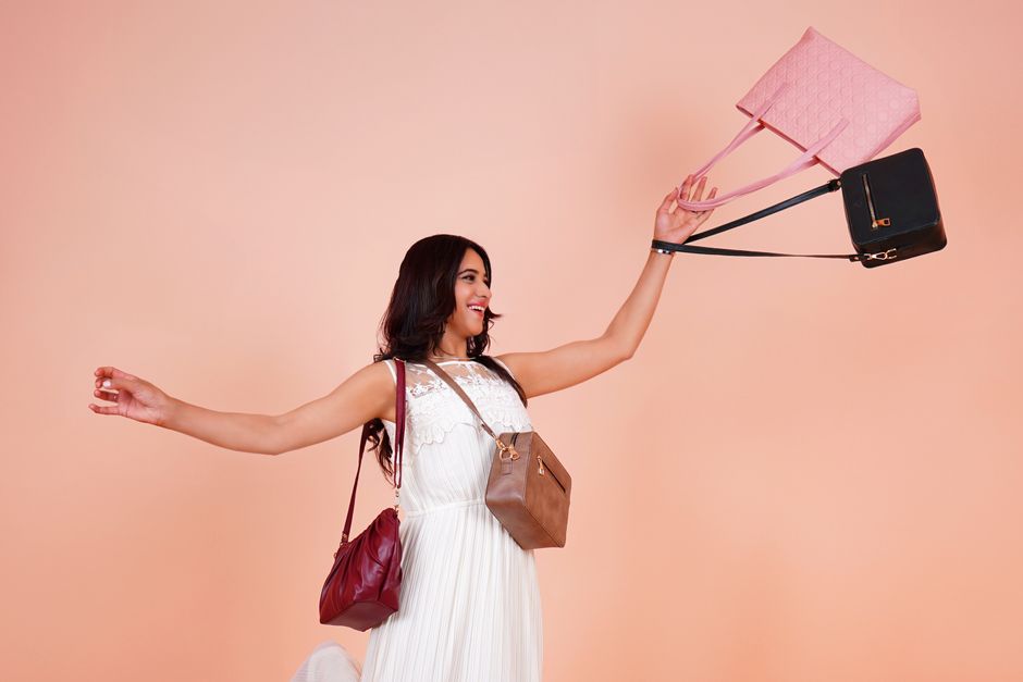 Fashion model holding elegant handbags against a pastel background, displaying glamour and style.